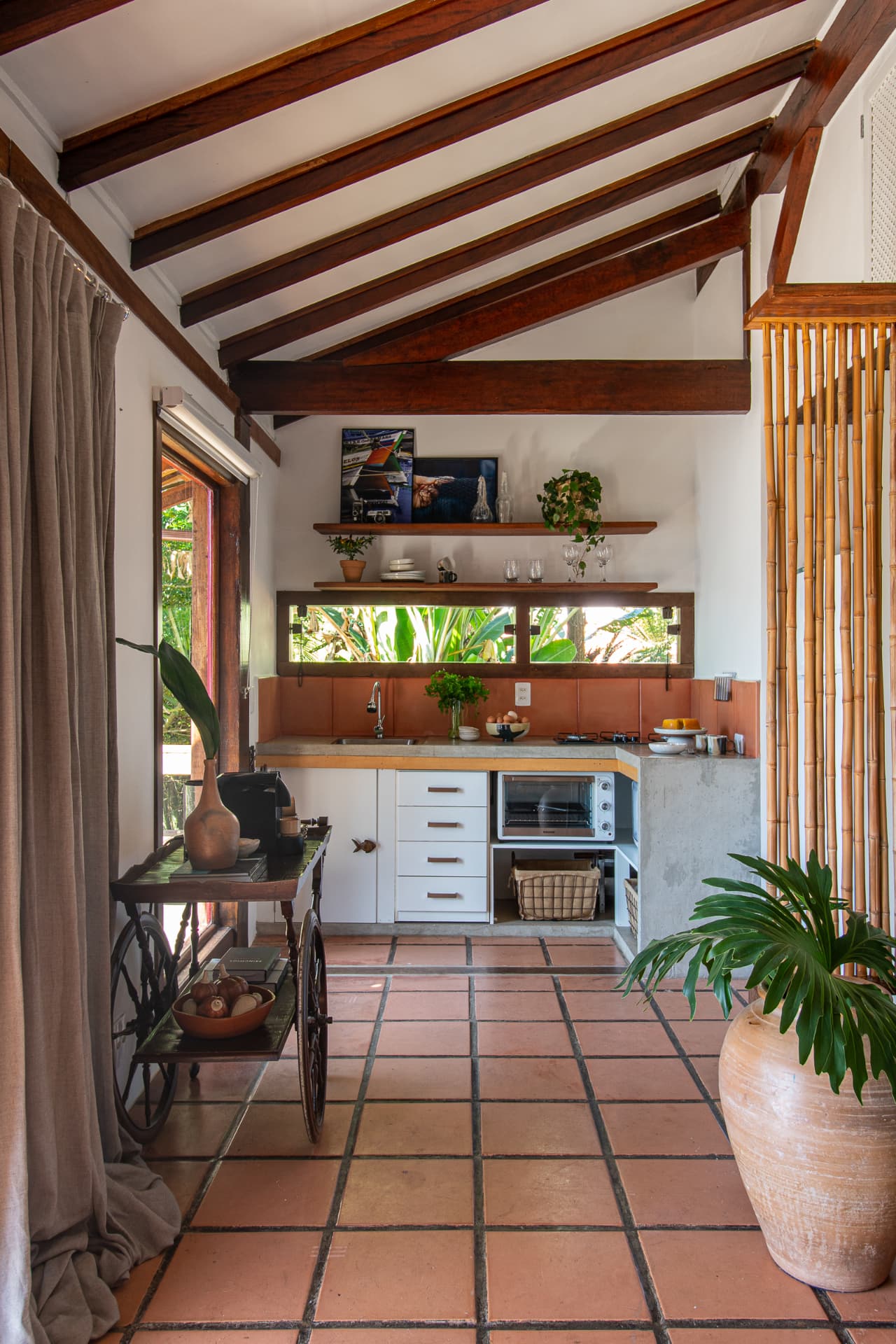 Cozinha revestida em barro, com a vegetação tropical pela janela